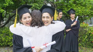 iki Asyalı kız öğrencilere mezuniyet önlük ve şapka üst kutlama töreni sarılmak..