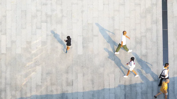 İnsanlar zeminde siyah siluet gölgesi olan yaya beton arazisinde yürür (üst hava manzarası))