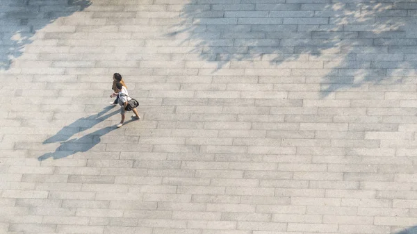 人们走过行人的混凝土景观 地面上有黑色的轮廓影子 高空鸟瞰 — 图库照片