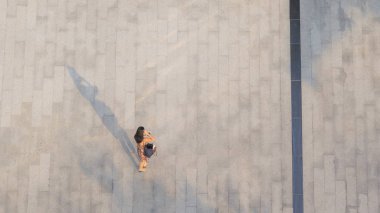 Telefonu olan kadın yaya üzerinde yürüyor, yerde siyah gölgesi var. (Üst hava manzarası))