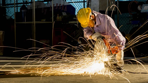 worker uses grinding cut metal, focus on flash light line of sharp spark,in low light