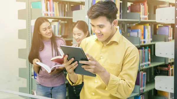 Asiático Adolescente Homem Tablet Com Meninas Falar Livro Prateleira Fundo — Fotografia de Stock