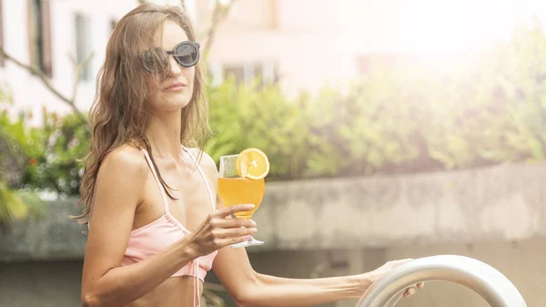 swimming suite sexy woman with beverage of orange cocktail at swimming pool