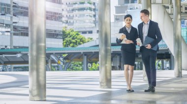 İş kadını elinde hamburgerle ve beyaz adamla mutlu bir şekilde konuşuyor.