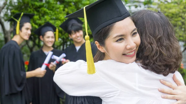kız öğrenci mezuniyet önlük ve şapka ile sarılmak üst kutlama töreni.