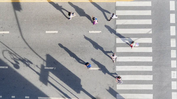 グループのトップの空中ビュー太陽と影のシルエットと交通渋滞の道路で歩行者横断歩道で街を歩く人々 — ストック写真