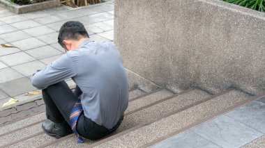 Yerde yayalar üzerinde oturan bir iş adamı. Ofisteki işini kaybettikten sonra üzgün, yorgun, hayal kırıklığına uğramış, hayal kırıklığına uğramış hissediyordu. İş dünyası mutsuz yaşam konsepti.