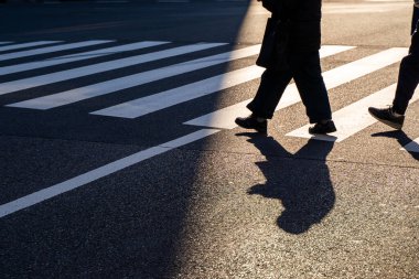 Silüet üst görünümü insanlar yaya yaya yaya geçidinde yürüyorlar akşam gün batımında caddede karanlık bir gölgeyle.