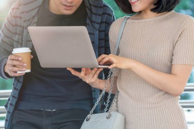 Bilgisayarlı Asyalı kız ve erkek öğrenci yaz günü açık havada konuşuyorlar. Eğitim ve teknoloji yaşam tarzı kavramı.