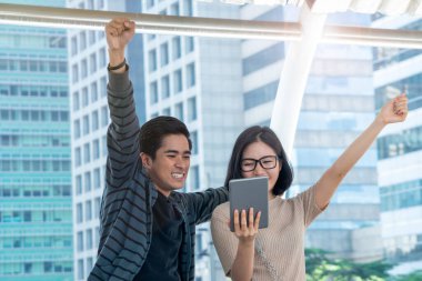 Dokunmatik tabletli Asyalı kız ve erkek öğrenci yaz günü açık havada konuşuyorlar. Eğitim ve teknoloji yaşam tarzı kavramı.