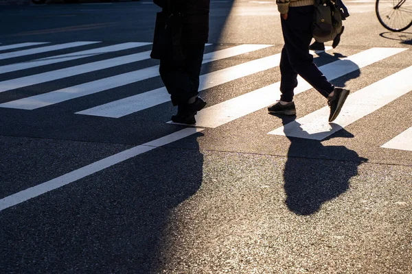 シルエットトップビューの人たちが交差点を歩いている夕日の交差点を通りの暗い影で歩いている — ストック写真