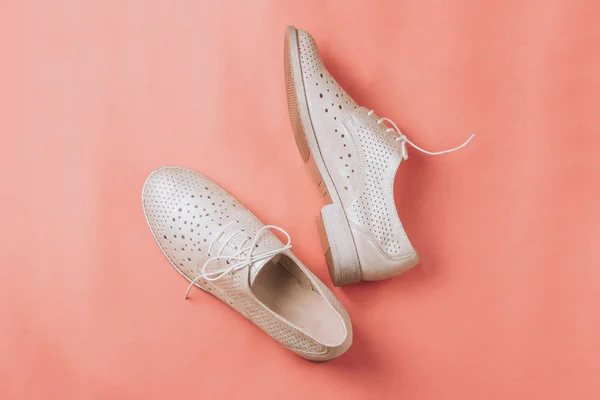 beige oxford shoes on pink background. Top view