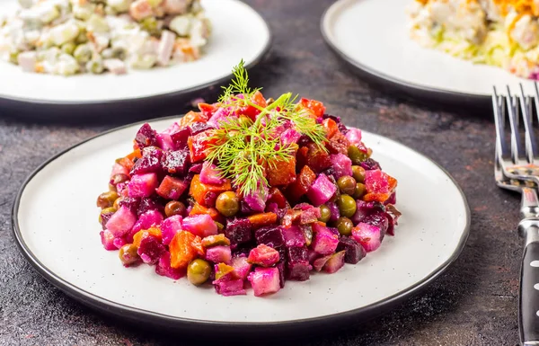 Russian food on dark background. Assortment salad of Russian cuisine - Olivier salad, vinaigrette - beet salad, herring salad. Top view. Copy space.