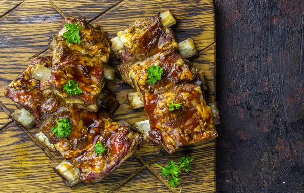 Smoked Roasted pork ribs over black background. Barbeque spicy ribs. Traditional american BBQ food. Dinner for a low-carb, keto diet