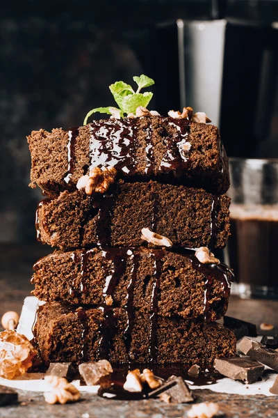 Homemade dark chocolate brownies topping with nut slices and mint stacked on dark table with copy space. Delicious bitter sweet and fudge. Brownie is one type of chocolate cake. American cuisine.