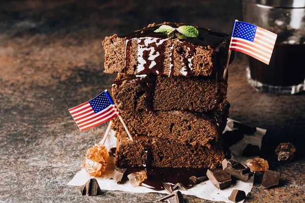 Homemade dark chocolate brownies topping with nut slices and mint stacked on dark table with copy space. Delicious bitter sweet and fudge. Brownie is one type of chocolate cake. American cuisine.