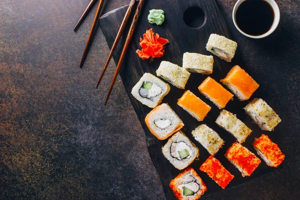 Japanese cuisine california roll and tuna roll on black wooden board served with wasabi and soy sauce