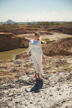 Uçurumun kenarında oturan beyaz elbiseli seksi kız.