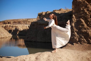 Uçurumun kenarında oturan beyaz etekli seksi kız.