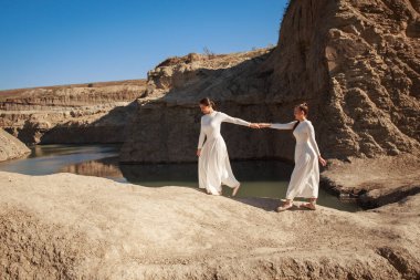 Uçurumun kenarında oturan beyaz etekli seksi kız.