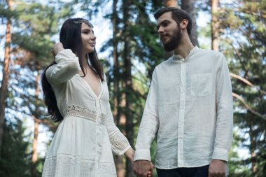 Aşık genç güzel Slav çift ormanda, bir basit boho-tarzı gelinlik tatlı kız yürüyor. Onlar mutlu ve sakin vardır. Yaz gün, sıcak, altın saat. Onlar öp, sarılmak ve el ele.