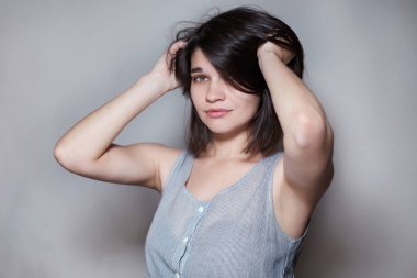 Omzunun hemen altında saçları ile güzel bir esmer, saçlarını düzleştiren, o güzel ve çok kadınsı, kamera bakarak, yakın çekim.