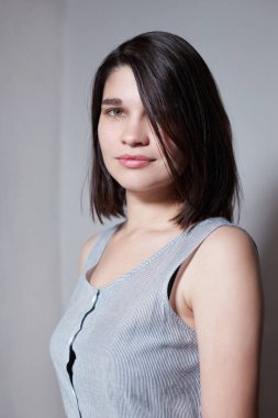 Omzunun hemen altında saçları ile güzel bir esmer, saçlarını düzleştiren, o güzel ve çok kadınsı, kamera bakarak, yakın çekim.