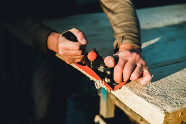 Adam woodworker marangoz El uçak ile çalışma. Bir tahta planya talaşı uçuyor. Usta el işçiliği.