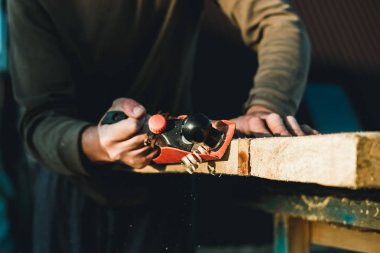 Adam woodworker marangoz El uçak ile çalışma. Bir tahta planya talaşı uçuyor. Usta el işçiliği.