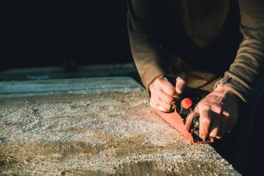 Adam woodworker marangoz El uçak ile çalışma. Bir tahta planya talaşı uçuyor. Usta el işçiliği.