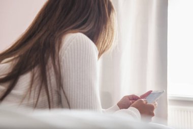 Yatakta akıllı cep telefonu kullanan bir kadın bakış