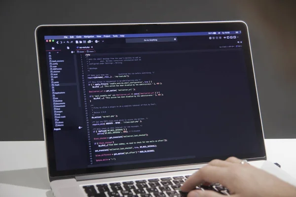 Male programmer working on laptop computer at white desk in office — Stock Photo, Image