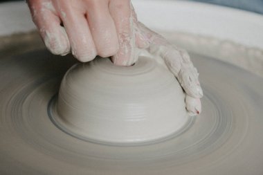 Bir kavanoz ya da vazo dolusu beyaz kil yakın plan. Kadın elleri kilden sürahi yapıyor..