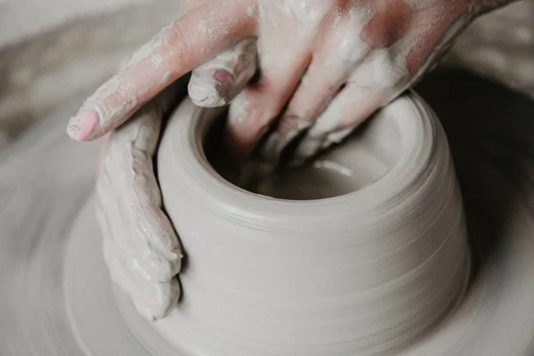 Creating a jar or vase of white clay close-up. Woman hands making clay jug.