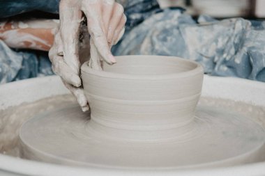 Bir kavanoz ya da vazo dolusu beyaz kil yakın plan. Kadın elleri kilden sürahi yapıyor..