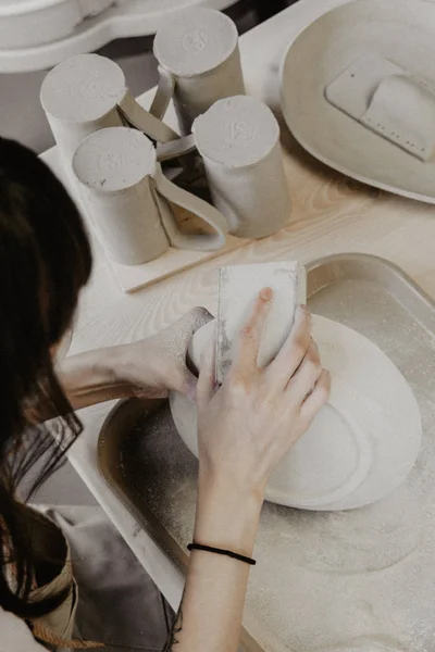 Una donna che fa ceramiche. Primo piano del processo di levigatura della lastra di argilla — Foto Stock