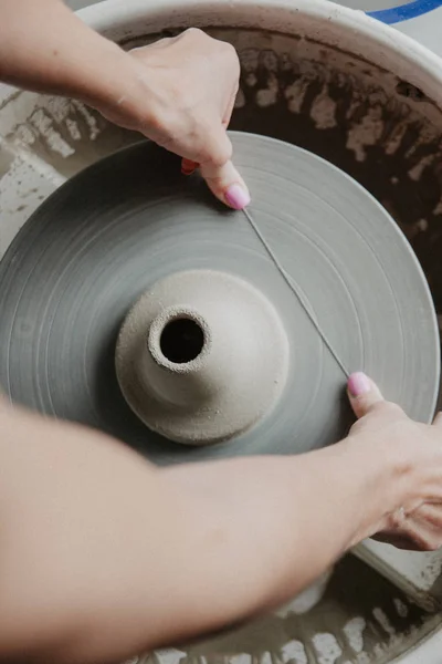 Mãos femininas cortando vaso de barro com arame de oleiro — Fotografia de Stock