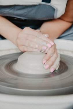 Bir kavanoz ya da vazo dolusu beyaz kil yakın plan. Kadın elleri kilden sürahi yapıyor..