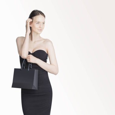 Close-up alışveriş torbaları üzerinde beyaz arka plan ile boşaltmak izole tutarak siyah elbise giyen güzel kız