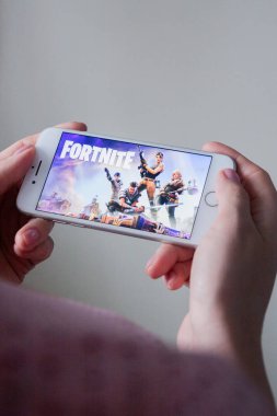 Los Angeles, California, USA - 8 March 2019: Hands holding a smartphone with Fortnite game on display screen, Illustrative Editorial clipart