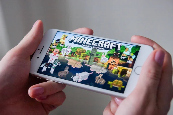 Los Ángeles, California, EE.UU. - 8 de marzo de 2019: Manos sosteniendo un teléfono inteligente con Minecraft Pocket Edition juego en pantalla, Editorial ilustrativo — Foto de Stock