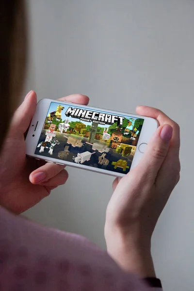 Los Ángeles, California, EE.UU. - 8 de marzo de 2019: Manos sosteniendo un teléfono inteligente con Minecraft Pocket Edition juego en pantalla, Editorial ilustrativo — Foto de Stock