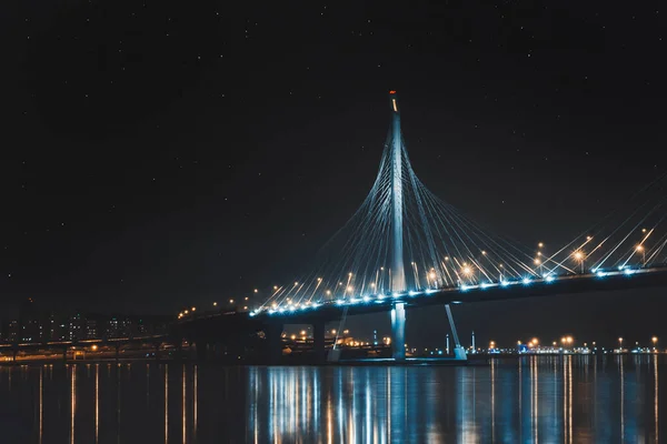 Beautiful cable-stayed bridge in St. Petersburg, Russia, with starry sky and cozy city lights — Stock Photo, Image