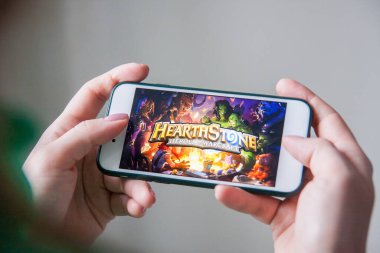 Los Angeles, Kaliforniya, ABD - 25 Şubat 2019: Hearthstone giriş ekranında akıllı telefonu tutan eller