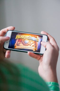 Los Angeles, Kaliforniya, ABD - 25 Şubat 2019: Hearthstone giriş ekranında akıllı telefonu tutan eller