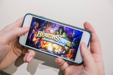 Los Angeles, Kaliforniya, ABD - 25 Şubat 2019: Hearthstone giriş ekranında akıllı telefonu tutan eller