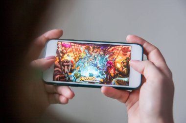 Los Angeles, Kaliforniya, ABD - 25 Şubat 2019: Hearthstone giriş ekranında akıllı telefonu tutan eller