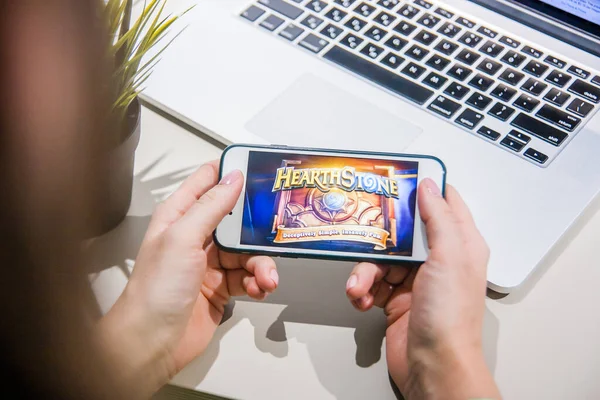 Los Angeles, Kaliforniya, ABD - 25 Şubat 2019: Hearthstone giriş ekranında akıllı telefonu tutan eller