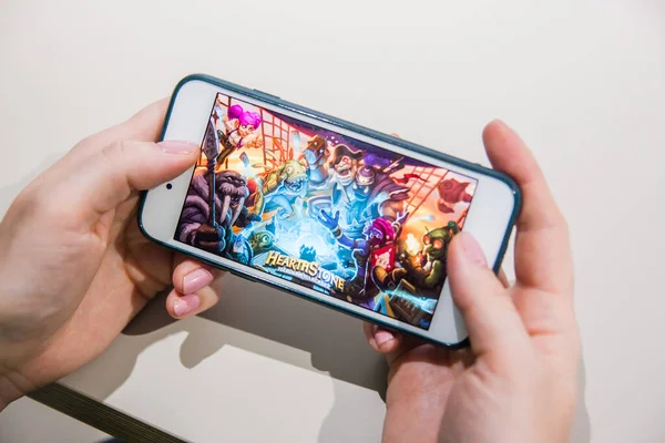 Los Ángeles, California, EE.UU. - 25 de febrero de 2019: Manos sosteniendo un teléfono inteligente con la introducción de Hearthstone en la pantalla — Foto de Stock