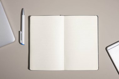 Bilgisayarlı bir ofis masası ve boş defterli bir akıllı telefon. Kopyalama alanı olan üst görünüm, düz yatay.